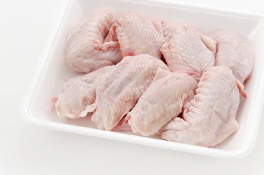 Beyaz plastik bir kabın içinde çiğ ve çiğ tavuk kanadı.