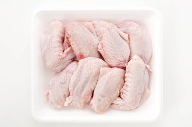 Beyaz plastik bir kabın içinde çiğ ve çiğ tavuk kanadı.