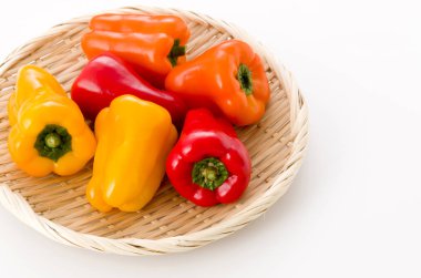 Beyaz arka planda bambu süzgecinde taze renkli dolma biber.