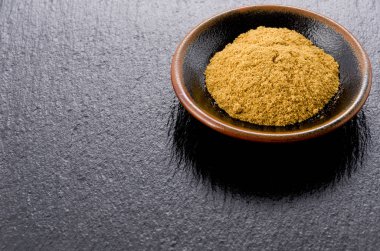 Siyah taş plaka üzerinde küçük siyah tabakta kimyon tozu