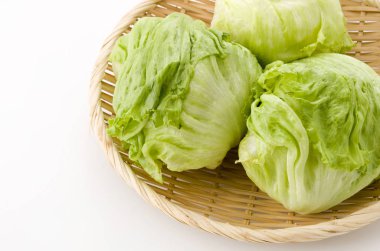 Beyaz arka planda bambu süzgecinde taze marul yaprakları