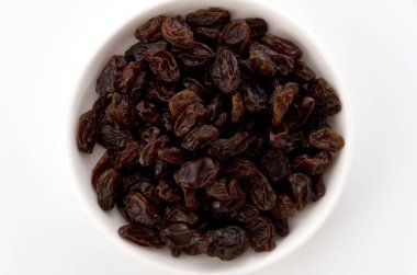 Kuru üzümler beyaz arkaplanda küçük tabakta