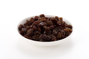 Kuru üzümler beyaz arkaplanda küçük tabakta