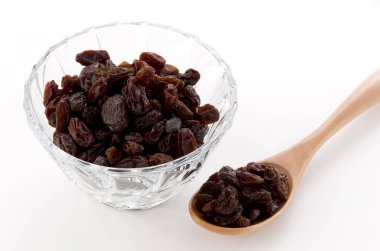 Beyaz arka planda cam kasede kuru üzümler