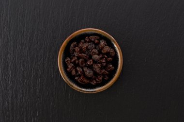 Siyah taş zemin üzerinde küçük tabakta kuru üzümler