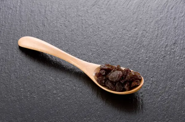 Raisins Dans Une Cuillère Bois Sur Fond Pierre Noire — Photo