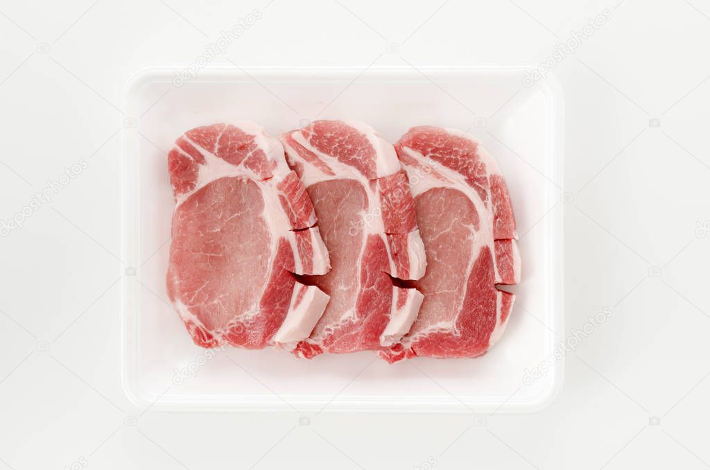 Raw pork meat in foam tray on white background