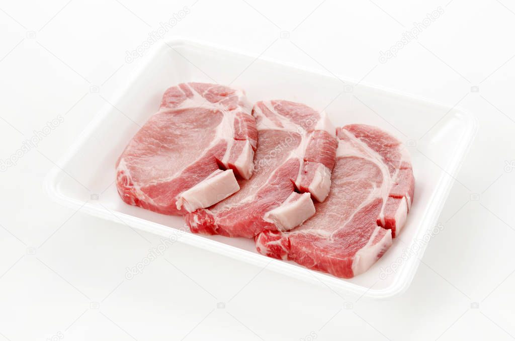 Raw pork meat in foam tray on white background