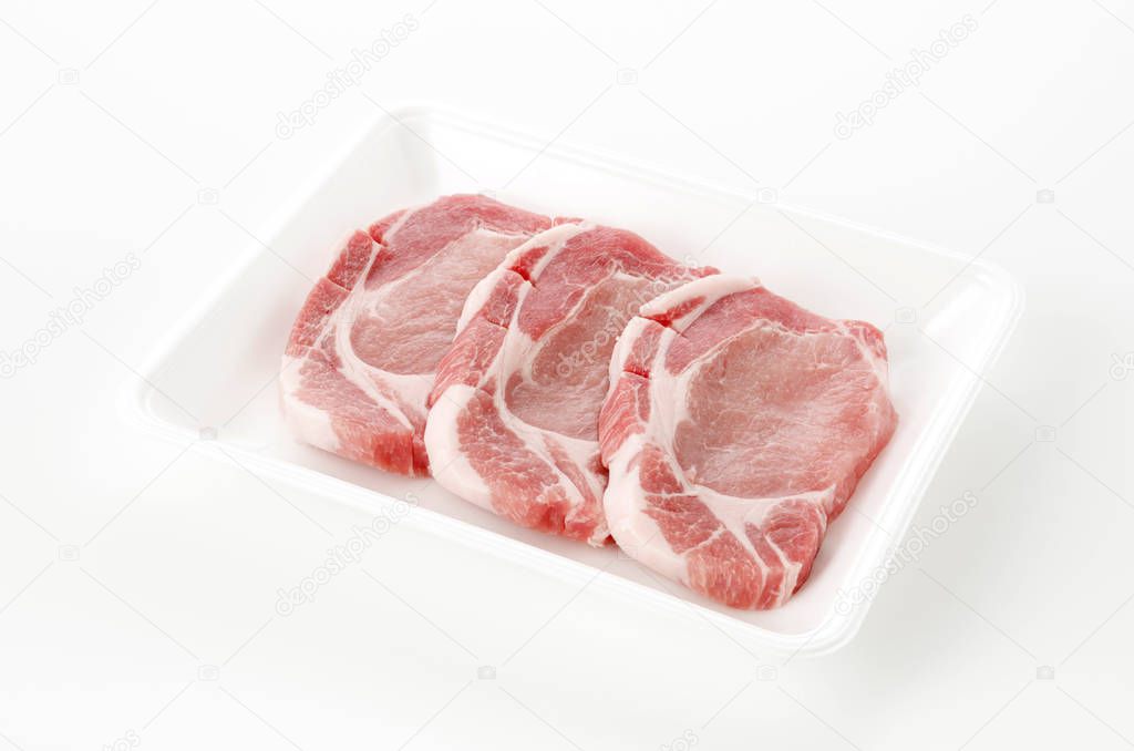 Raw pork meat in foam tray on white background