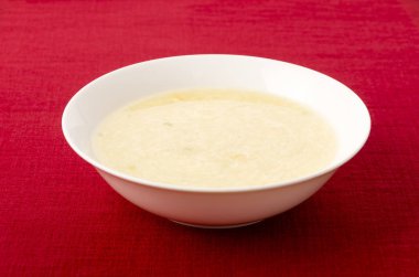 Tatlı mısır yumurtası çorbası beyaz tabakta kırmızı bez üzerinde
