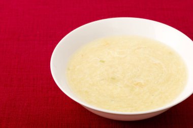 Tatlı mısır yumurtası çorbası beyaz tabakta kırmızı bez üzerinde