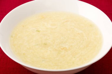 Tatlı mısır yumurtası çorbası beyaz tabakta kırmızı bez üzerinde