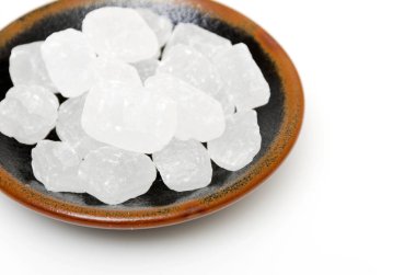 Beyaz arkaplanda bir tabakta kaya şekeri