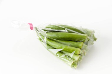 Beyaz arka planda plastik poşette taze bamya