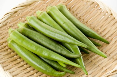 Beyaz arka planda bambu süzgeci üzerine taze bamya