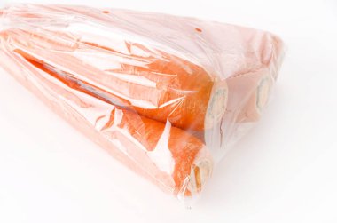 Beyaz arka planda plastik poşette taze havuç.