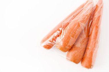 Beyaz arka planda plastik poşette taze havuç.