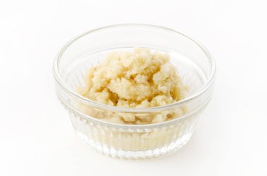 Beyaz arka planda cam kasede rendelenmiş zencefil