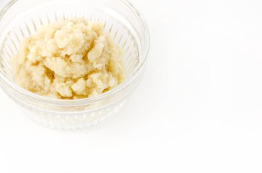 Beyaz arka planda cam kasede rendelenmiş zencefil