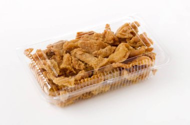 Beyaz arka planda plastik bir kapta kızarmış tavuk derisi. 