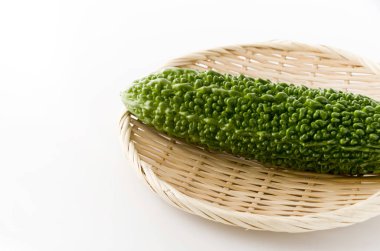 Goya, beyaz arka planda bambu süzgecinde acı kavun.