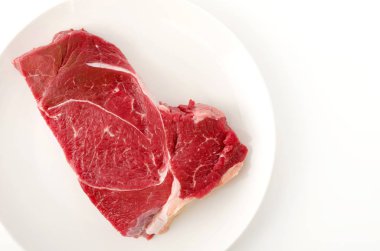 Beyaz arka planda bir tabakta yuvarlak biftek..