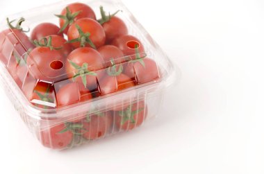 Plastik bir kap içinde kiraz domates. Beyaz arka plan üzerinde kutusunda taze kiraz domates.