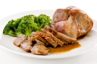 Soslu kızarmış domuz eti ve beyaz tabakta brokoli.