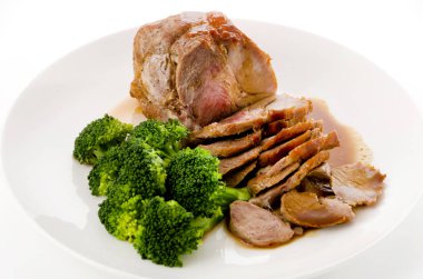 Soslu kızarmış domuz eti ve beyaz tabakta brokoli.