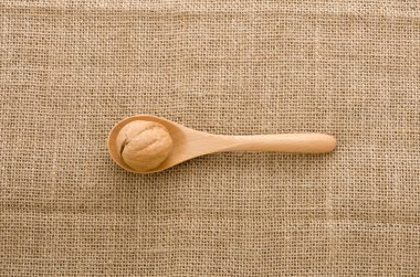 Çuval arka plan üzerinde tahta bir kaşık ceviz