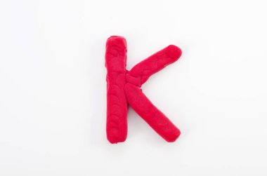 Beyaz arkaplanda izole edilmiş İngiliz alfabesinin K büyük harfi kırmızı plasticine.