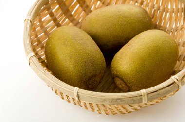 Beyaz arkaplanda bambu süzgeci üzerine altın kivi