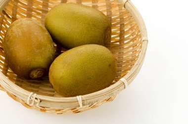 Beyaz arkaplanda bambu süzgeci üzerine altın kivi