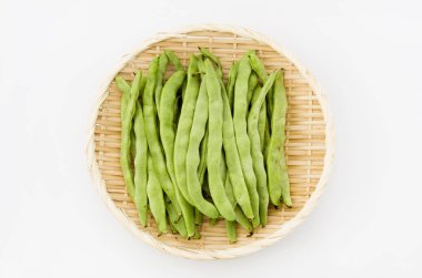 Beyaz arka planda bambu elek üzerinde düz yeşil fasulye