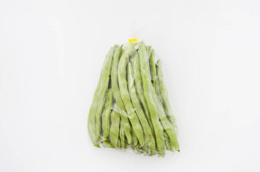 Beyaz arka planda plastik torbada düz yeşil fasulye.