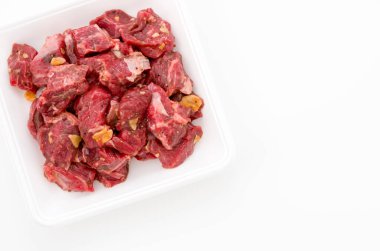 Baharatlı çiğ et parçaları köpük tepside beyaz arka planda. Chuck göz devirme.