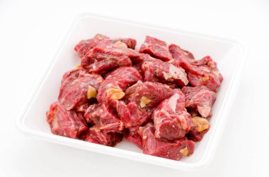 Baharatlı çiğ et parçaları köpük tepside beyaz arka planda. Chuck göz devirme.