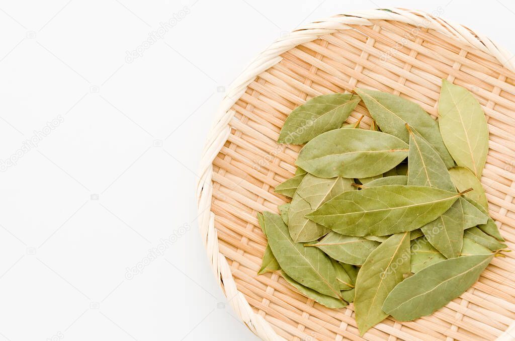Dried bay leaves on bamboo sieve on white background.
