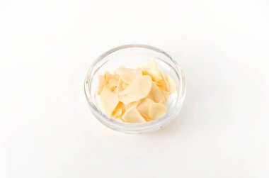 Beyaz arka planda istiflenmiş sarımsak cipsi.