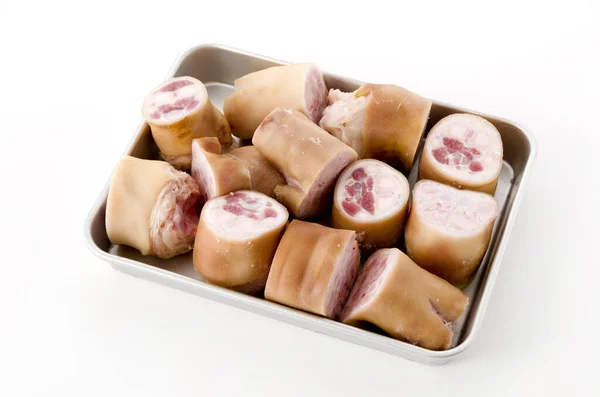 fresh raw pig's feet on aluminum tray on white background