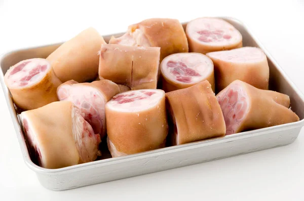 fresh raw pig's feet on aluminum tray on white background