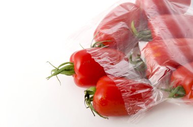 Beyaz zemin üzerinde şeffaf plastik poşet içinde San Marzano domatesleri