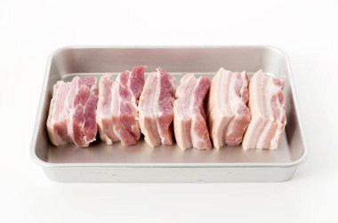 Beyaz arkaplanda alüminyum tepside taze domuz eti.
