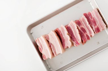 Beyaz arkaplanda alüminyum tepside taze domuz eti.