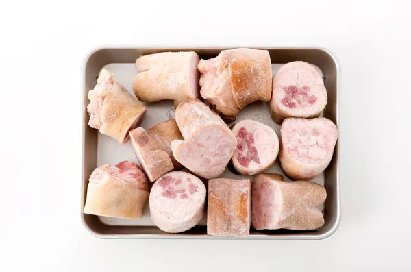 fresh raw pig's feet on aluminum tray on white background