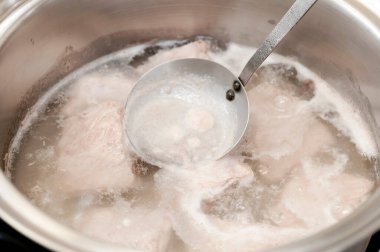 Gaz ocağında paslanmaz çelik tencereyle kaynayan suda domuz eti.. 