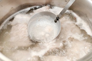 Gaz ocağında paslanmaz çelik tencereyle kaynayan suda domuz eti.. 