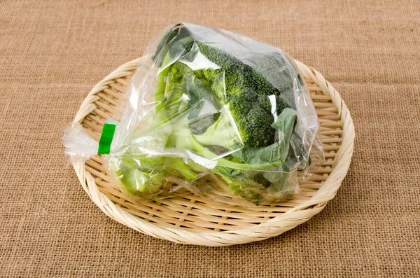 fresh broccoli in transparent plastic bag on a bamboo sieve on burlap