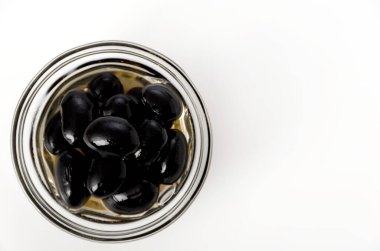 Beyaz arka planda cam kasede siyah fasulye kaynatılmış.