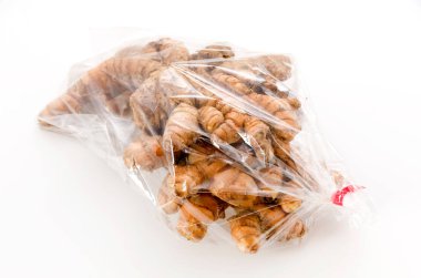 Beyaz zemin üzerinde plastik poşette yabani zerdeçal (Curcuma aromatica salisb)
